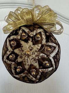 a christmas ornament hanging from the ceiling with gold bows and decorations on it