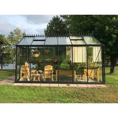 a small glass house sitting on top of a lush green field