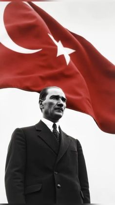 a black and white photo of a man in front of a flag with a turkey on it