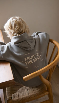 a little boy sitting at a table with his back to the camera, wearing a sweatshirt that says fruit of the spirit