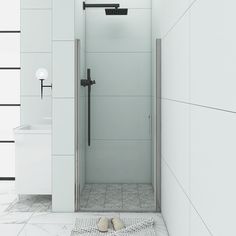 a white tiled bathroom with a walk in shower next to a sink and towel on the floor