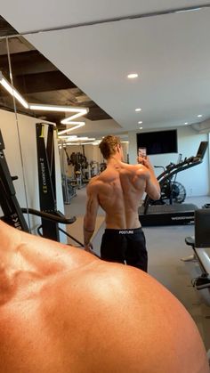 a shirtless man taking a selfie in the gym