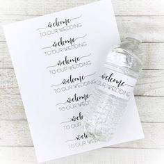 a bottle of water sitting on top of a piece of paper next to a card