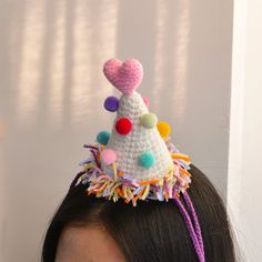 Celebrate in Style with our Crocheted Birthday Party Hat!  Make every moment a celebration with our whimsical Crocheted Birthday Party Hat! 🥳 Crafted with love, this white arrow-shaped hat is adorned with randomly placed colorful pompoms, topped with a charming pink heart, and features a vibrant purple tie string. The base of the hat is a burst of festive colors, adding a touch of joy to your special occasions. Key Features: 🎈 **Colorful Pompom Accents Randomly placed, vibrant pompoms add a pl Birthday Hat Crochet Pattern, Adjustable Crochet Party Hat, Pom Pom Party Hats, Crochet Party Hat, Crochet Birthday Hat, Whimsical Handmade Crochet Festival Hat, Multicolor Novelty Party Hat, Birthday Crochet, Fun Hat