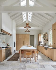 a large kitchen with an island in the middle and wooden cabinets on both sides, along with skylights