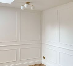 an empty room with white walls and wood flooring is pictured in this image, there are two lamps on either side of the wall