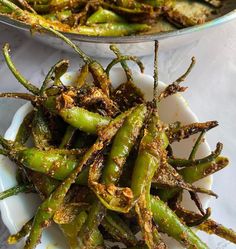 green beans in a white bowl on a table with another dish behind it and the other side