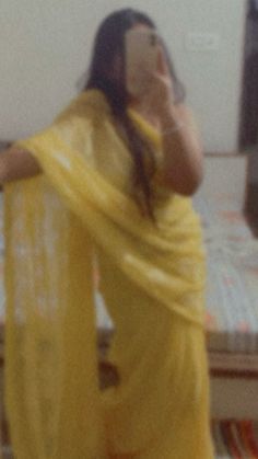 a woman in a yellow sari taking a selfie