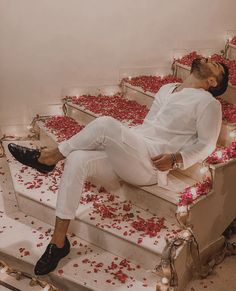 a man sitting on some steps with rose petals all over the floor and in front of him