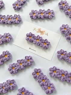 purple crochet flowers are arranged on a white surface next to a greeting card