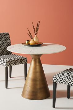 a table with two chairs and a bowl of fruit sitting on top of the table