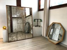 a large mirror sitting on top of a hard wood floor next to a white wall