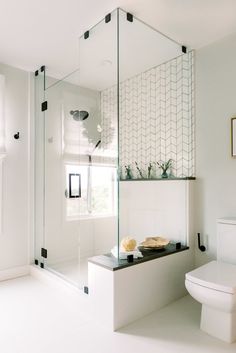 a bathroom with a toilet, sink and glass shower enclosure in the middle of it