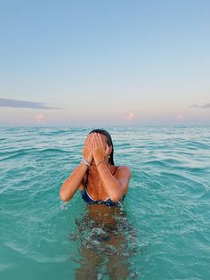 a woman covers her eyes while floating in the ocean