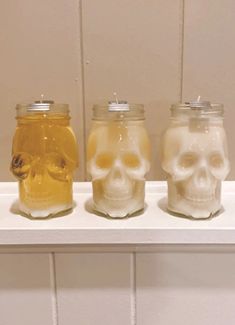 three jars filled with different types of liquid sitting on top of a shelf next to each other