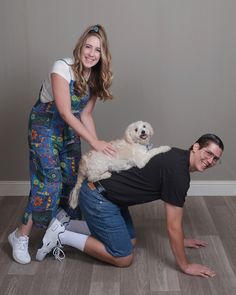 a man and woman pose with a dog on the floor in front of a wall