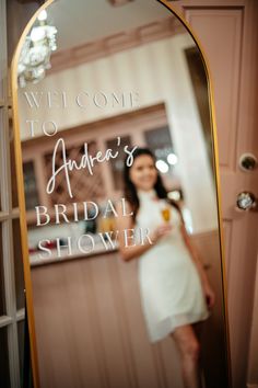 a woman standing in front of a mirror with the words welcome to amber's bridal shower