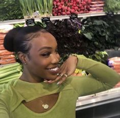 a woman standing in front of a display of vegetables at a grocery store with her hands on her head