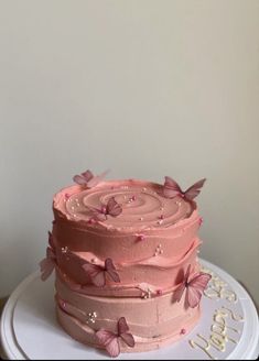 a three layer pink cake with butterflies on it