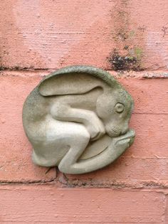 a stone sculpture of a baby fish on a brick wall