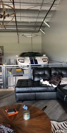 a living room filled with furniture and a car parked in the garage behind it's doors