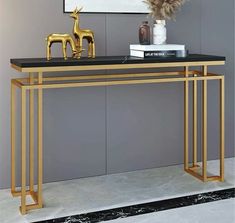 a black and gold console table with two golden deer figurines next to it