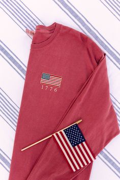 Most sizes and colors are available to ship next day! I love this USA shirt. God Bless the USA! These vintage inspired embroidered American flags are perfect for showing your patriotism this summer at your Fourth of July celebrations! Embroidered on your choice of a Comfort Colors tank, tee, long sleeve, crewneck sweatshirt, or quarter zip. 4tb Of July, Usa Graphic Tee, American Flag Embroidery, Long Sleeve Tops For 4th Of July, Long Sleeve Cotton Tops For 4th Of July, Cotton Long Sleeve Top For 4th Of July, Long Sleeve American Style Cotton Sweatshirt, American Style Cotton Long Sleeve Sweatshirt, Cotton Tops With Flag Print For Fall