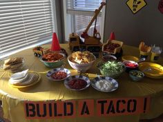 a table topped with lots of food next to a construction truck and building signs on the wall