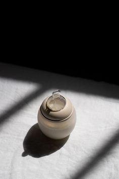 an empty jar sitting on top of a white sheet with the light coming through it