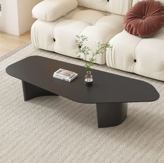 a black coffee table sitting on top of a rug in front of a white couch