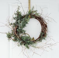 a wreath hanging on the front door with branches and twigs around it, ready to be hung