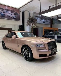 a pink rolls royce parked in a showroom