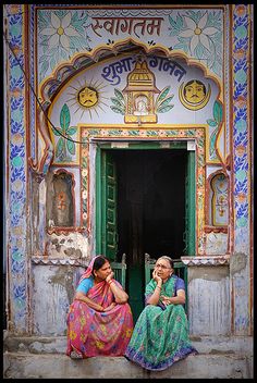 two women sitting on the steps of an old building