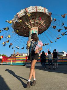 a woman holding a stuffed animal in front of a carnival ride