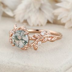 a close up of a ring on a white cloth with flowers in the back ground