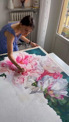 a woman is working on an art project with flowers painted on the floor and in front of her