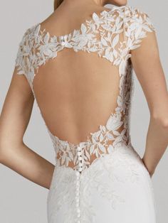 the back of a wedding dress with white flowers on it