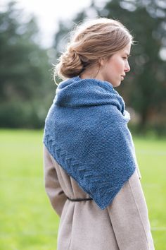 a woman wearing a blue shawl standing in a field