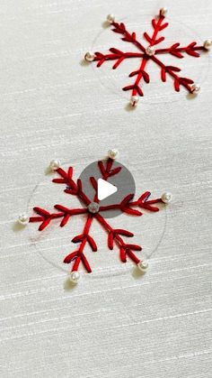 two red snowflakes sitting on top of a white cloth covered table next to each other