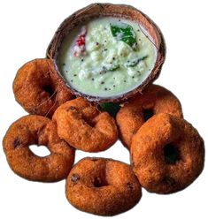 several doughnuts and dip in a bowl on a white background