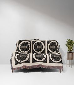 a black and white blanket sitting on top of a couch next to a potted plant