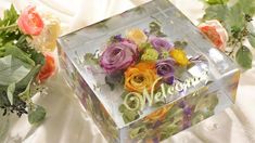 there is a clear box with flowers in it and the word welcome written on it