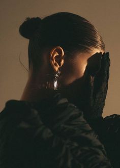 a woman with her hand on her face and ear piercings in front of her