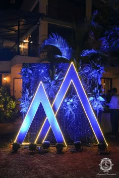 blue lights are lit up in the shape of three pyramids on display at an outdoor event