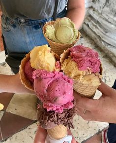 three scoops of ice cream are stacked high on top of each other in cones