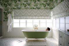 a green bath tub sitting under a window in a bathroom