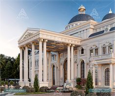 a large white building with columns and arches on the front, surrounded by greenery