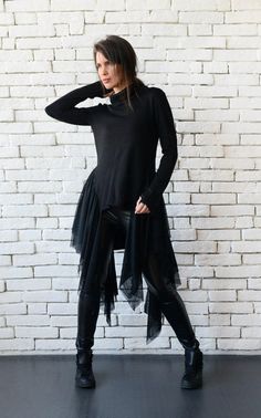 Extravagant black tunic - METT0098 A gorgeous tunic that is very gentle and sits lovely on every lady. This interesting design is a mixture of urban style culture and femininity - it has a polo neckline and thumb hole sleeves but the lower part consists of a beautifully draping tulle Black Lagenlook Blouse With Asymmetrical Hem, Black Asymmetrical Tunic For Spring, Fall Lagenlook Tunic Blouse, Black High-low Hem Top For Fall, Black Long Sleeve Tunic For Fall, Black Asymmetrical Chic Tunic, Chic Black Asymmetrical Tunic, Chic Black Tunic For Layering, Black Spring Tunic For Layering