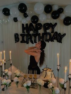 a woman is kissing her husband in front of a birthday cake with candles and balloons