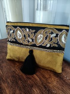 This silk kutnu clutch will bring elegance to your style. It will be chic with jeans or dresses and you may use this clutch bag both day and night. This clutch bag is perfectly handmade with high quality handwoven silk kutnu fabric. Designed with a silk bohemian embroidery and tassel. Clutch has an interfacing and a padding inside to stand upright. Closes with a zipper. This bag is designed to fit all the things you need for comfortable everyday busy life. There will be enough space for smart ph Festive Evening Bags With Tassels, Festive Gold Bag With Tassels, Elegant Festive Bags With Tassels, Elegant Festive Tassel Bags, Festive Party Bags With Tassels, Elegant Festival Bags With Tassels, Bohemian Embroidered Gold Evening Bag, Bohemian Gold Embroidered Evening Bag, Gold Bohemian Embroidered Clutch